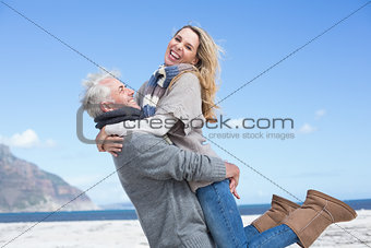 Smiling couple having fun on the beach in warm clothing