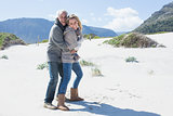 Smiling couple hugging on the beach in warm clothing