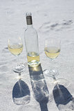 White wine bottle and glasses on the sand