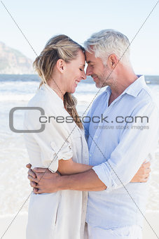 Happy couple hugging on the beach looking at each other