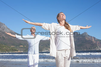 Happy couple standing with arms outstretched at the beach
