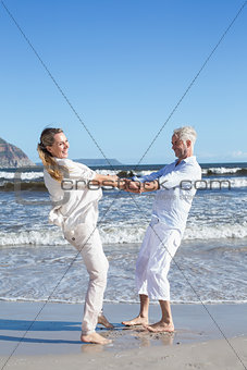Smiling couple spinning on the beach
