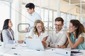Casual business team having a meeting using laptop