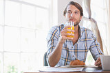 Handsome man drinking orange juice at breakfast