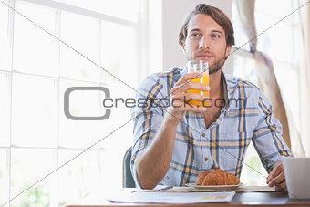Handsome man drinking orange juice at breakfast