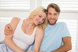 Young couple sitting on the couch smiling at camera