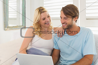 Young couple sitting on the couch together using laptop