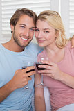 Happy couple having red wine on the couch