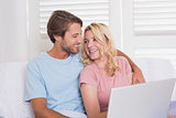 Happy couple relaxing on the couch with laptop