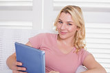 Happy blonde relaxing on the couch with tablet pc