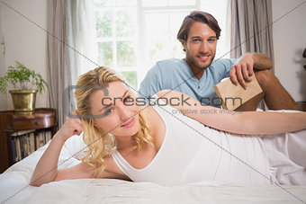 Happy couple relaxing on bed smiling at camera