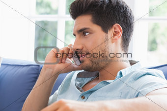 Attractive man making a call on the couch