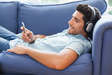 Attractive man lying on the couch listening to music