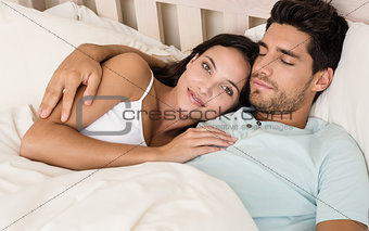 Attractive couple lying in bed smile at camera