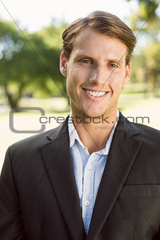 Handsome businessman in the park smiling at camera