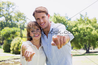 Cute couple pointing to the camera in the park