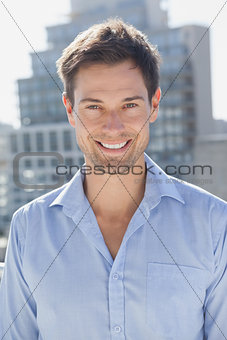 Handsome man smiling at camera on his balcony