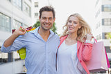 Stylish young couple smiling at camera holding shopping bags