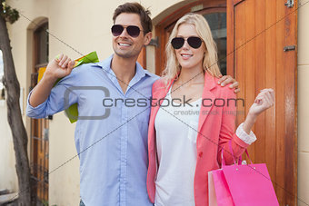 Stylish young couple standing with shopping bags