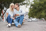 Cute young couple sitting on skateboard kissing