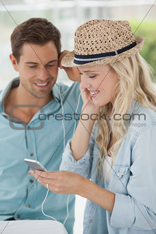 Cute couple listening to music together in cafe