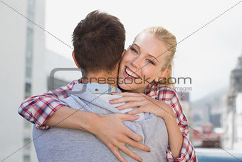 Hip young couple hugging with woman smiling at camera