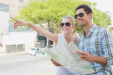 Young tourist couple consulting the map and pointing