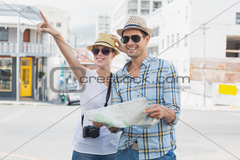 Young tourist couple consulting the map and pointing