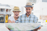 Young tourist couple consulting the map with magnifying glass