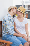 Young hip couple sitting on bench about to kiss
