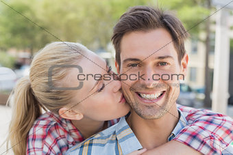 Young hip woman giving boyfriend kiss on the cheek