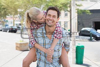 Young hip man giving his blonde girlfriend a piggy back