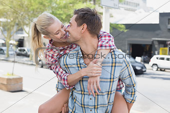 Young hip man giving his blonde girlfriend a piggy back