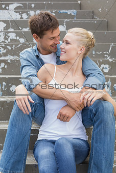 Hip young couple sitting on steps smiling at each other