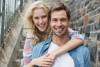Hip young couple sitting on steps smiling at camera