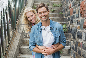 Hip young couple sitting on steps smiling at camera
