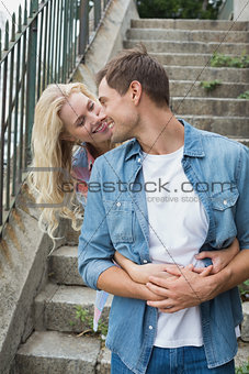Hip young couple standing by steps hugging
