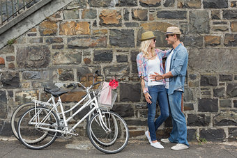 Hip young couple hugging by brick wall with their bikes