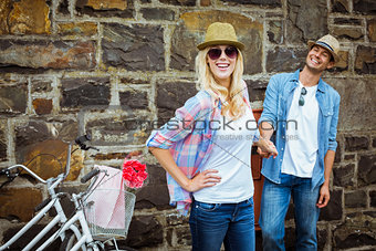 Hip young couple standing by brick wall with their bikes