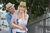 Hip young couple smiling at camera by railings