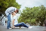Hip young blonde sitting on skateboard with boyfriend kissing forehead