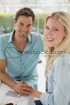 Hip young couple sitting at table smiling at camera