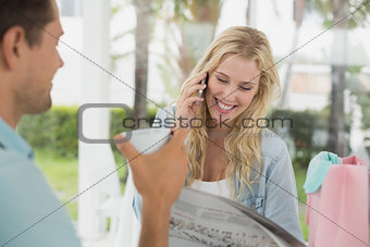 Pretty blonde talking on phone while having coffee with boyfriend