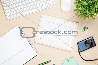 Photo frame on office table with notepad, computer and camera