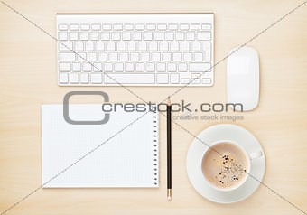 Office table with notepad, computer and coffee cup
