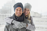 Cute couple in warm clothing hugging smiling at camera