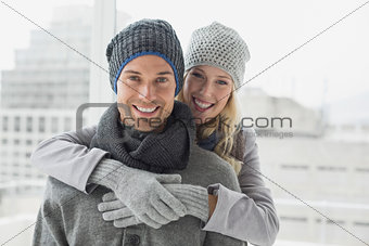 Cute couple in warm clothing hugging smiling at camera