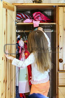 Cute little girl hanging up her clothes