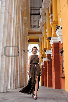 Girl in Greek style walking along marble columns