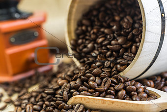 scattered roasted coffee beans from a wooden barrel and a wooden